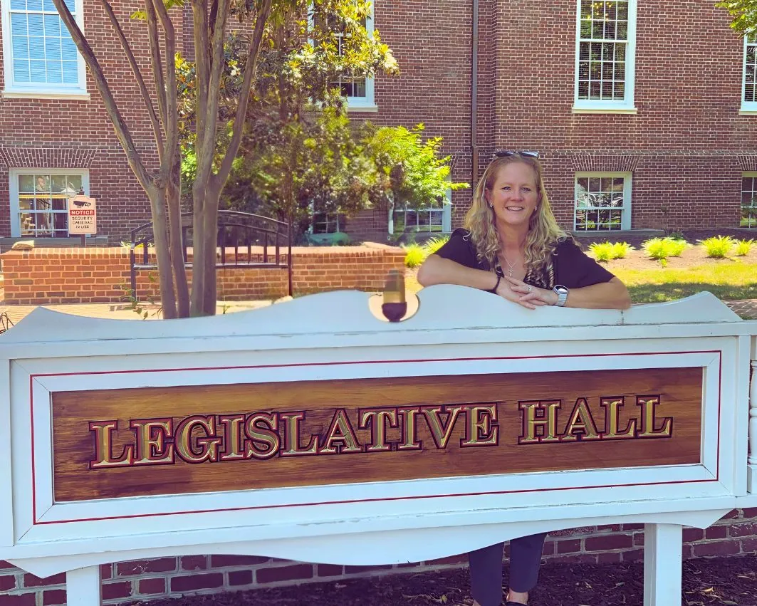 Penny Kubin standing behind the Legislative Hall sign in Dover, Delaware